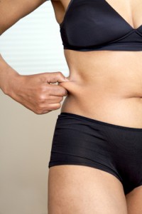 iStock_fit-woman_belly A fit woman holding her belly fat